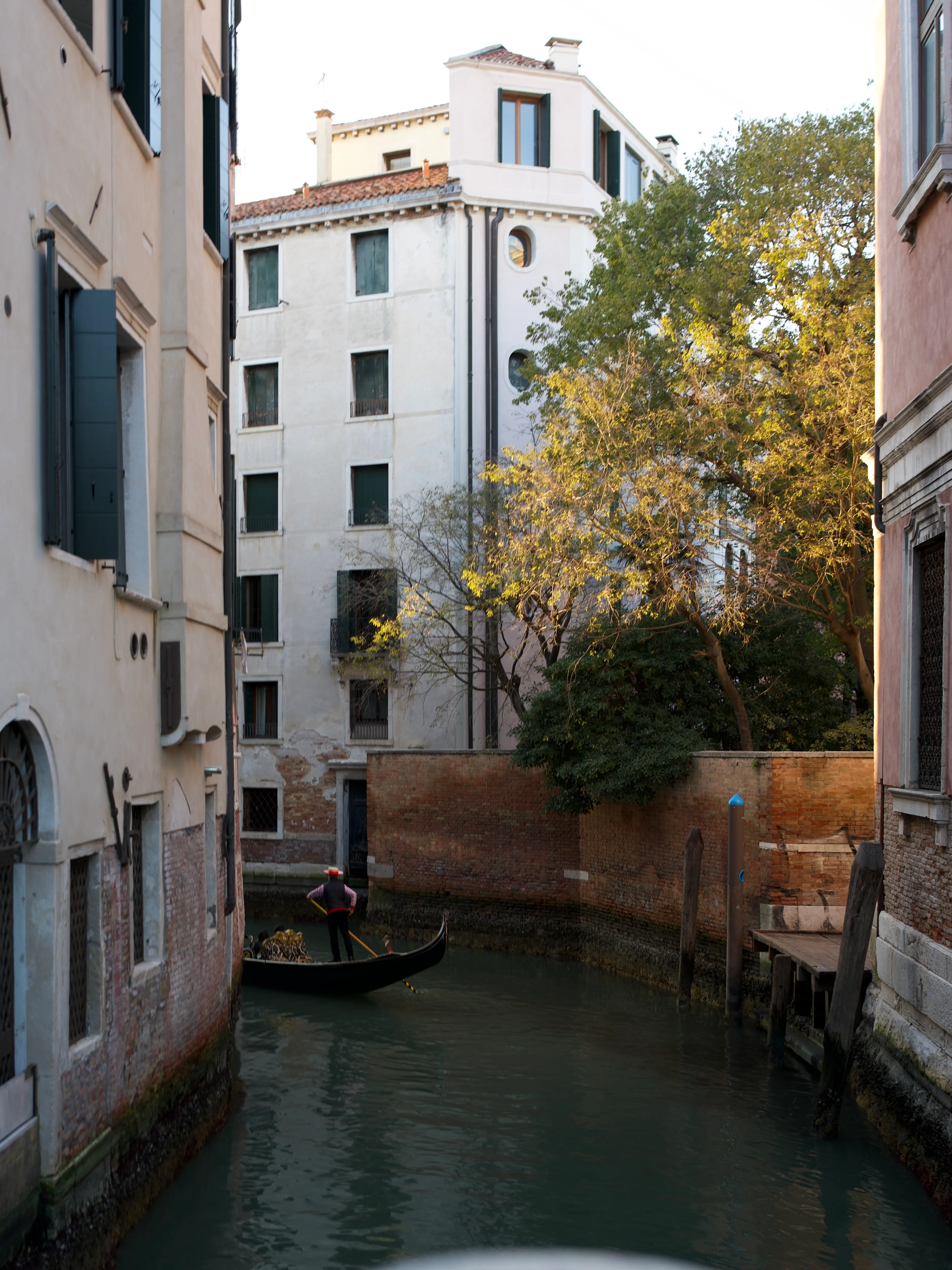 A gondoliere turning a boat around the corner of a small canal in Venice